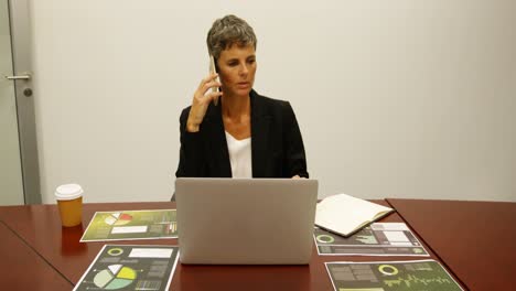 Businesswoman-talking-on-mobile-phone-at-desk-4k