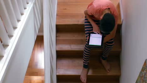 Boy-using-digital-tablet-while-sitting-on-the-staircase-4k