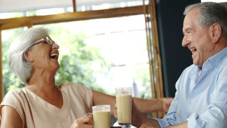 Senior-couple-with-coffee-mugs-laughing-and-embracing-4k