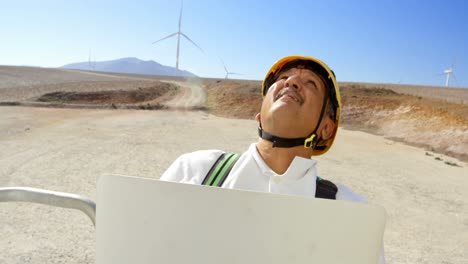 Male-engineer-using-laptop-in-the-wind-farm-4k