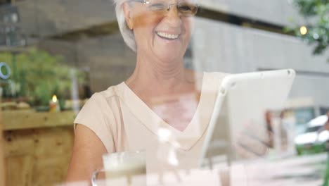 Senior-woman-using-digital-tablet-in-cafe-4k