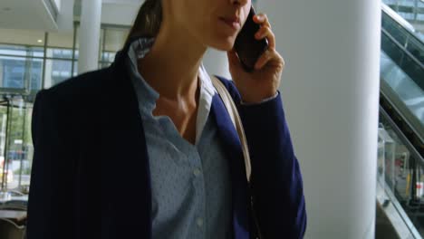 Businesswoman-with-suitcase-talking-on-the-phone-in-office-4k