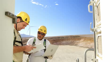 Two-engineer-discussing-over-laptop-in-the-wind-farm-4k