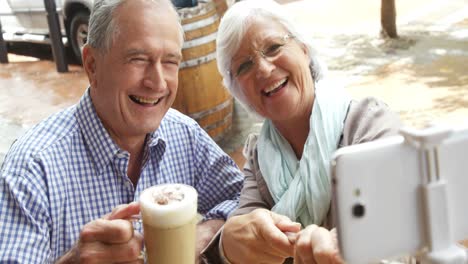 Senior-couple-taking-a-selfie-while-having-coffee-in-cafe-4k
