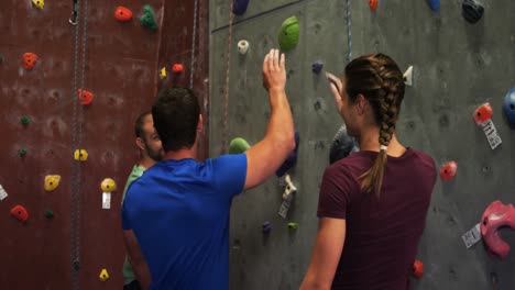 Man-and-woman-giving-a-high-five-while-climbing-an-artificial-wall-4k