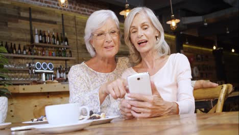 Senior-woman-discussing-over-the-phone-in-cafe-4k