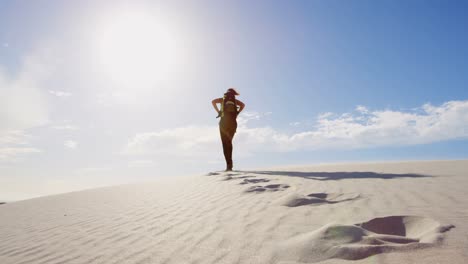 Woman-with-backpack-walking-in-the-desert-on-a-sunny-day-4k