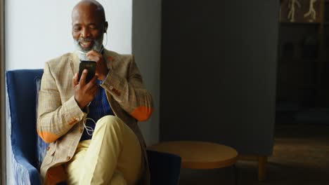 Senior-businessman-using-his-headphones-while-talking-on-the-mobile-phone-4K-4k