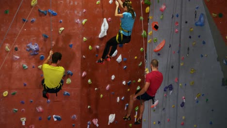 Men-and-woman-climbing-down-the-artificial-wall-at-bouldering-gym-4k