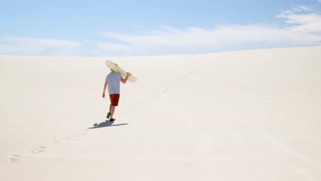 Man-with-sand-board-walking-in-the-desert-on-a-sunny-day-4k