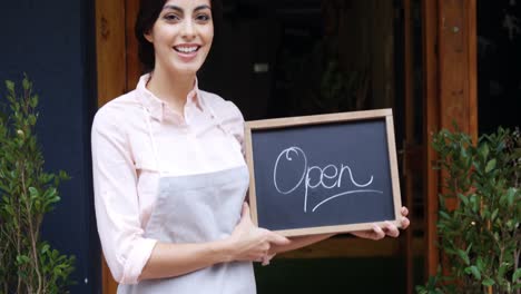 Female-waiter-standing-with-open-sign-board-4k