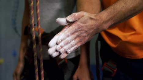 Man-rubbing-his-hands-with-chalk-powder-at-bouldering-gym-4k