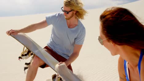 Man-rubbing-sand-over-the-sand-board-while-woman-watching-4k