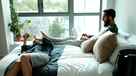Couple-using-laptop-and-mobile-phone-on-bed-4k