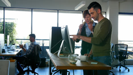 Executives-discussing-over-desktop-pc-at-desk-4k