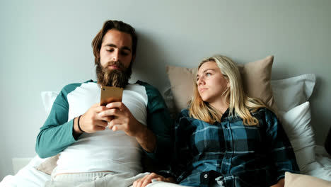 Couple-using-mobile-phone-on-bed-at-home-4k