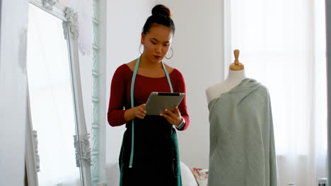 Fashion-designer-with-digital-tablet-working-on-dressmakers-model-4k