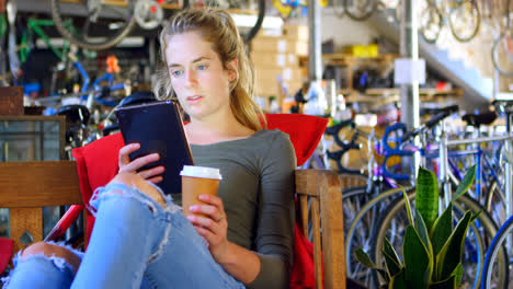 Mujer-Tomando-Café-Frío-Mientras-Usa-Una-Tableta-Digital-En-El-Taller-4k