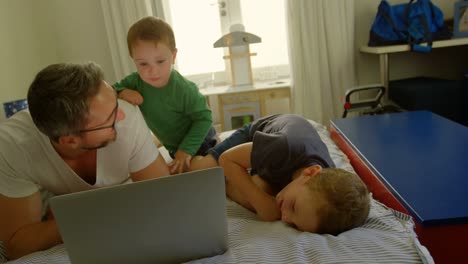 Father-and-kids-using-laptop-on-bed-4k