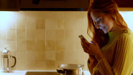 Woman-using-a-mobile-phone-in-kitchen-4k