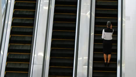 Businesswoman-using-escalator-while-talking-on-mobile-phone-4k