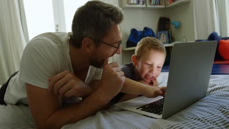Father-and-son-using-laptop-on-bed-4k