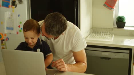 Father-and-son-using-laptop-in-kitchen-4k
