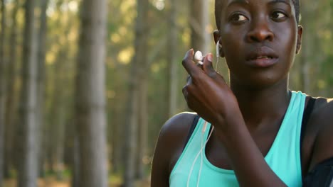 Female-jogger-putting-headphone-in-her-ear-4k