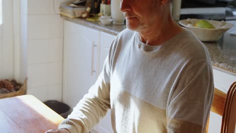 Senior-man-using-laptop-in-kitchen-4k