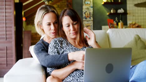 Lesbian-couple-using-laptop-on-sofa-4k