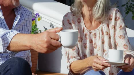 Senior-couple-with-coffee-cup-having-fun-on-porch-step-4k