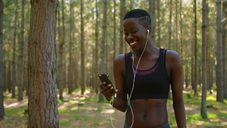 Female-jogger-using-mobile-phone-in-the-forest-4k