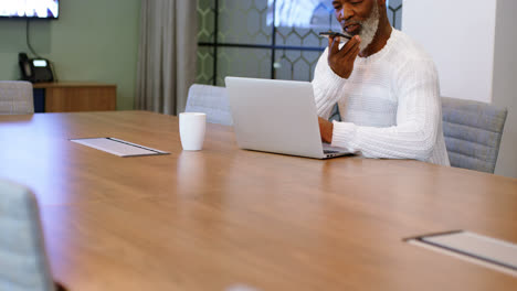 Senior-man-using-laptop-while-talking-on-mobile-phone-4k