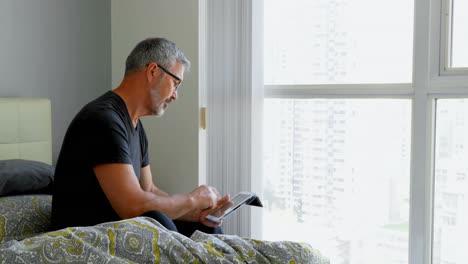 Man-using-digital-tablet-on-bed-at-home-4k