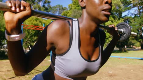 Female-athlete-exercising-with-weight-barbell-the-park-4k