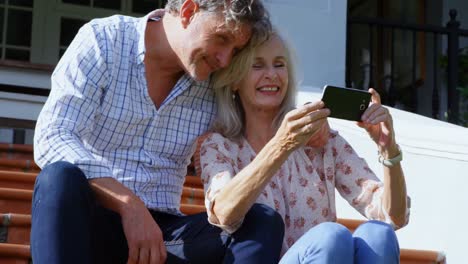 Senior-couple-using-mobile-phone-on-porch-step-4k