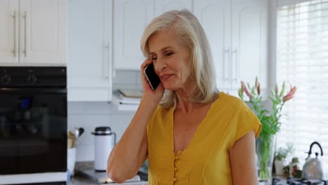 Senior-woman-talking-on-mobile-phone-in-kitchen-4k