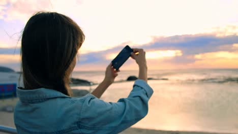 Woman-clicking-photos-with-mobile-phone-at-beach-4k
