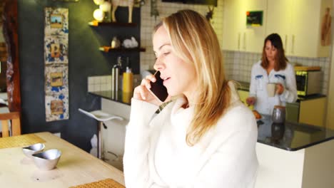 Lesbian-couple-having-coffee-and-talking-on-mobile-phone-4k