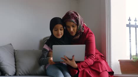 Mother-and-daughter-using-laptop-in-living-room-4k