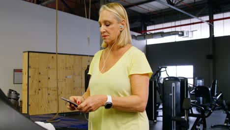 Senior-woman-using-mobile-phone-during-exercise-4k