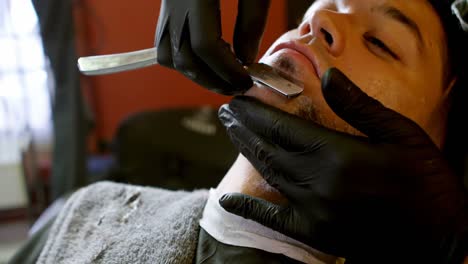 Man-getting-his-beard-shaved-with-straight-razor-4k