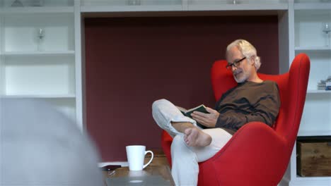 Senior-man-reading-a-book-in-living-room-4k