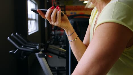 Senior-woman-talking-on-mobile-phone-during-exercise-in-fitness-studio-4k