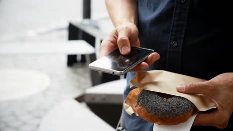 Mann-Mit-Donuts-Benutzt-Mobiltelefon-Im-Straßencafé-4k