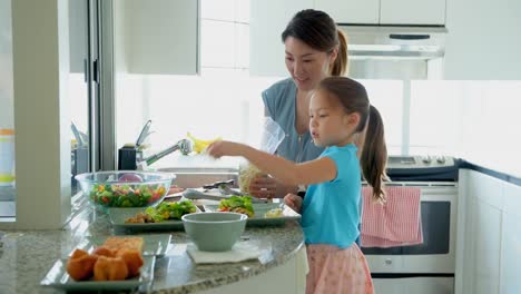 Mother-and-daughter-keeping-food-on-plate-in-kitchen-4k