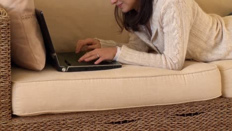 Mirthful-woman-lying-down-using-a-laptop