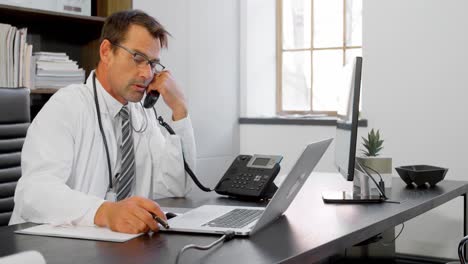 Physician-talking-on-landline-at-desk-4k