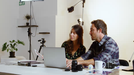 Photographers-discussing-over-laptop-at-desk-4k