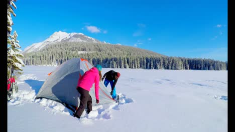 Couple-preparing-a-tent-on-snowy-landscape-4k